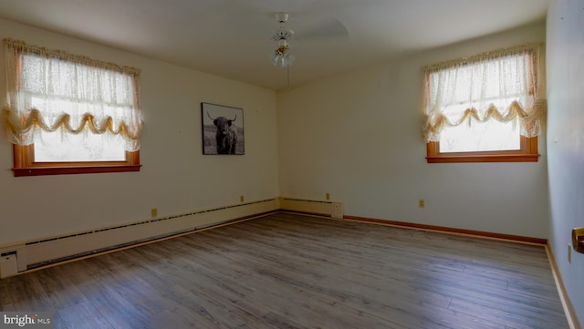 empty room featuring baseboard heating, ceiling fan, and hardwood / wood-style floors