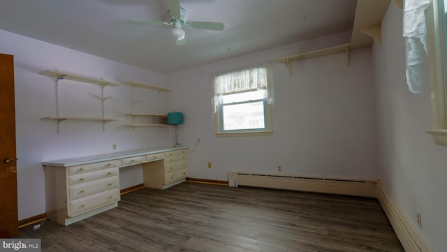 unfurnished office featuring built in desk, ceiling fan, a baseboard radiator, and dark wood-type flooring