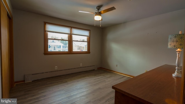 unfurnished bedroom with a baseboard heating unit, ceiling fan, a closet, and hardwood / wood-style floors