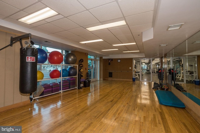 exercise area with a paneled ceiling and hardwood / wood-style floors