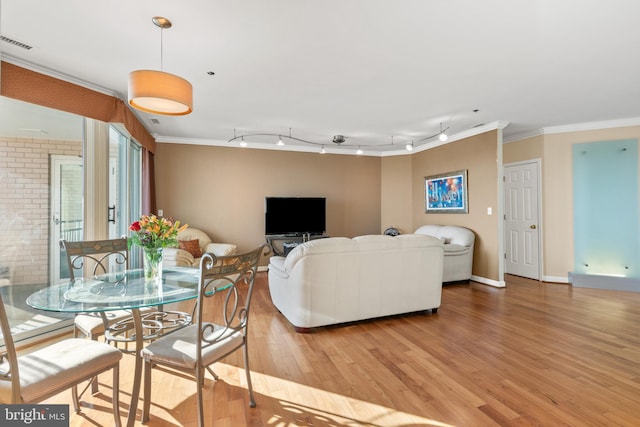 living room with ornamental molding, rail lighting, and light hardwood / wood-style flooring