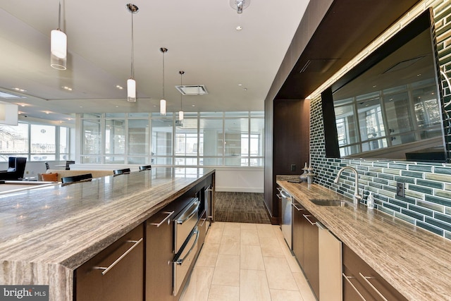 kitchen featuring dishwasher, sink, light stone counters, and decorative backsplash