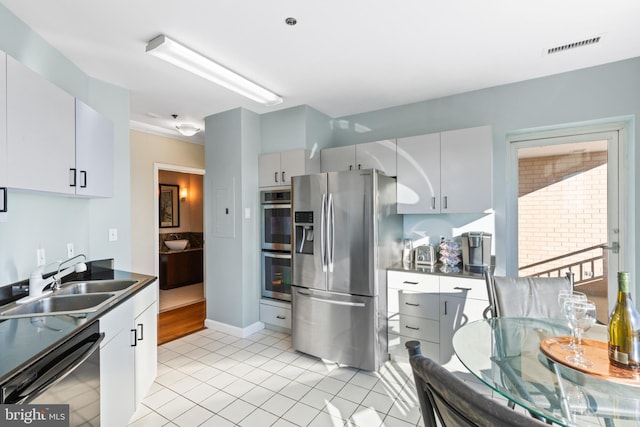 kitchen featuring stainless steel appliances, white cabinetry, sink, and light tile patterned floors