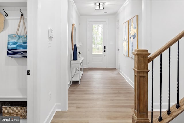 entryway with light hardwood / wood-style floors and crown molding