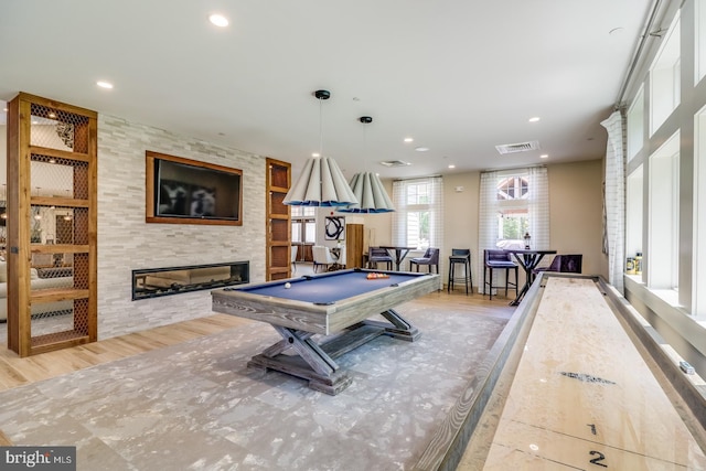 playroom featuring a tiled fireplace, light hardwood / wood-style flooring, billiards, and built in features