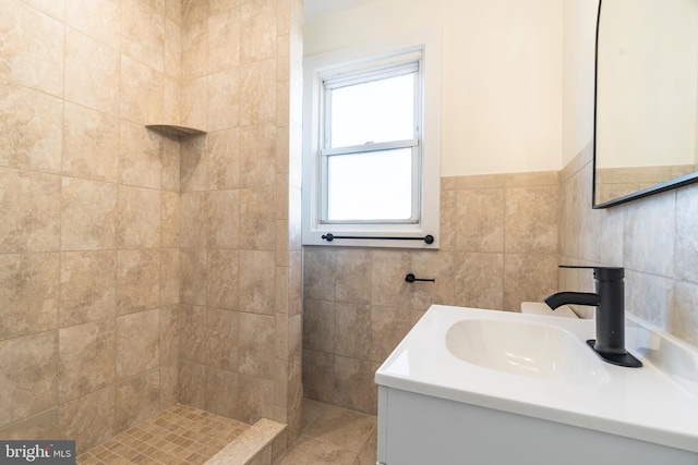 bathroom featuring tile walls, a tile shower, and vanity