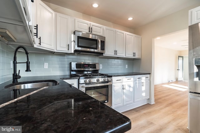 kitchen with light hardwood / wood-style flooring, decorative backsplash, white cabinetry, appliances with stainless steel finishes, and sink