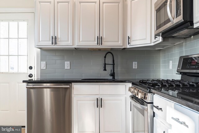 kitchen with sink, white cabinets, dark stone countertops, decorative backsplash, and appliances with stainless steel finishes