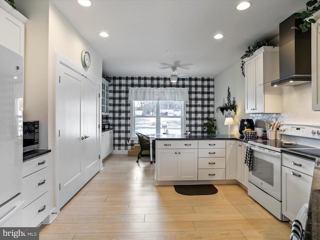 kitchen featuring white cabinetry, ceiling fan, fridge, wall chimney range hood, and white range with electric cooktop