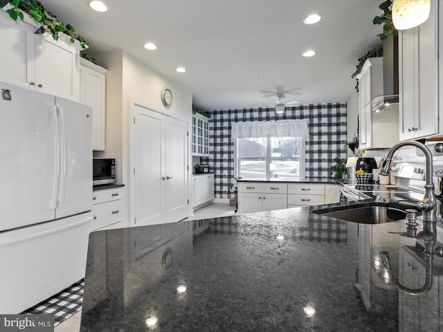 kitchen featuring sink, white cabinetry, white refrigerator, and dark stone countertops