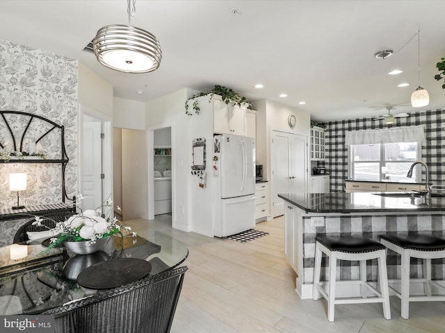 kitchen featuring washer / dryer, white fridge, sink, hanging light fixtures, and white cabinets