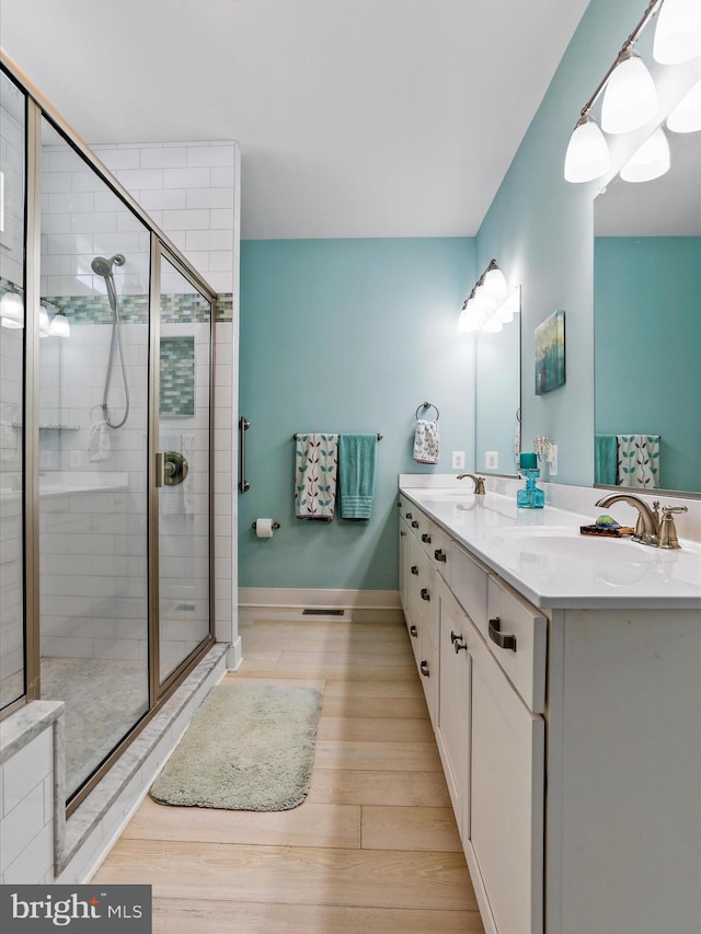 bathroom with walk in shower, vanity, and hardwood / wood-style flooring