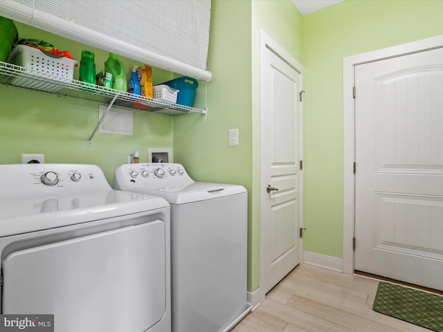 clothes washing area with washing machine and dryer and light hardwood / wood-style flooring