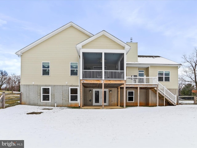 snow covered house featuring a deck and a sunroom