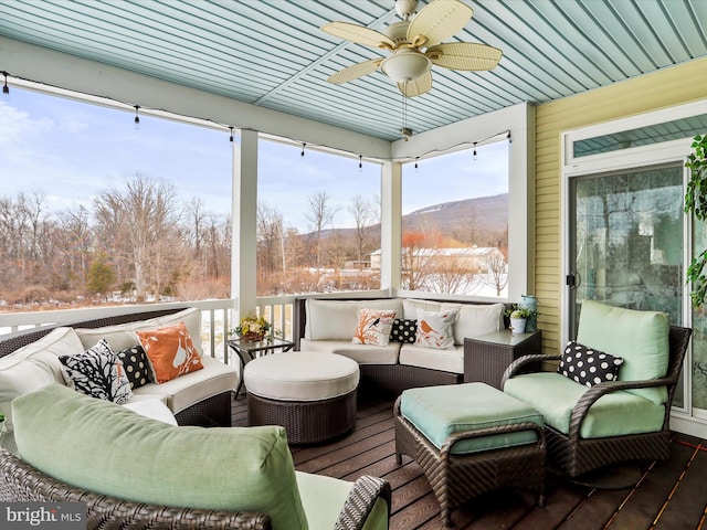 sunroom featuring ceiling fan, plenty of natural light, and a mountain view