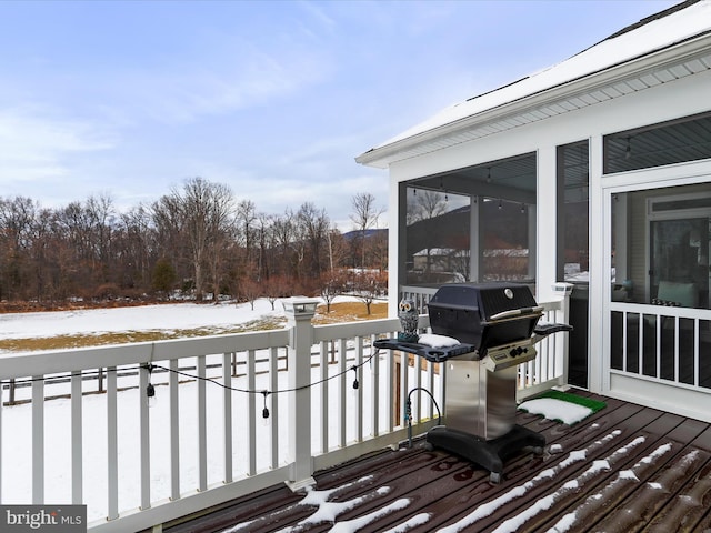 snow covered deck featuring a sunroom and area for grilling