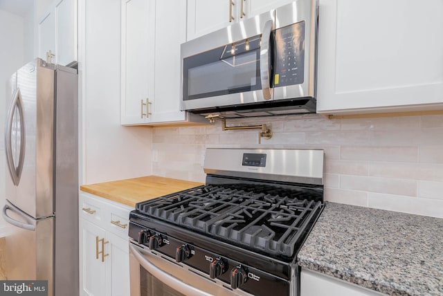 kitchen featuring light stone countertops, backsplash, appliances with stainless steel finishes, and white cabinetry