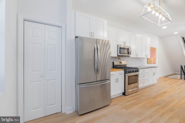 kitchen featuring light hardwood / wood-style floors, appliances with stainless steel finishes, decorative backsplash, decorative light fixtures, and white cabinets