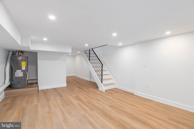 basement with light hardwood / wood-style flooring and water heater