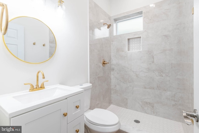 bathroom featuring toilet, vanity, and a tile shower