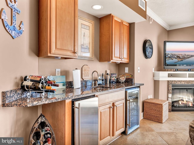 kitchen with crown molding, dark stone counters, wine cooler, sink, and high end refrigerator