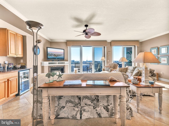 tiled living room featuring wine cooler, ceiling fan, crown molding, a textured ceiling, and a high end fireplace