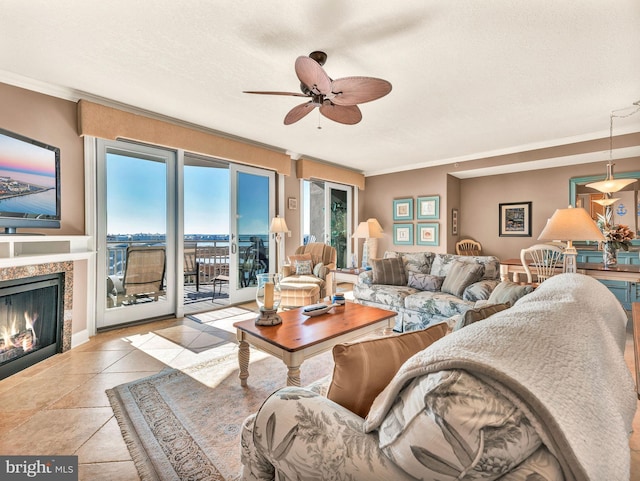 living room featuring ceiling fan, a textured ceiling, light tile patterned floors, and ornamental molding