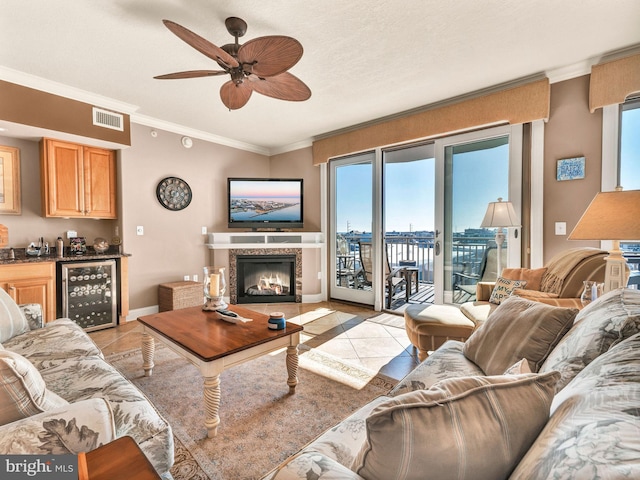 tiled living room featuring ceiling fan, crown molding, a premium fireplace, and wine cooler