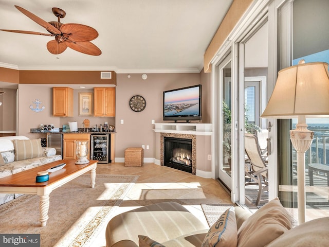 tiled living room featuring ceiling fan, crown molding, a tiled fireplace, and wine cooler