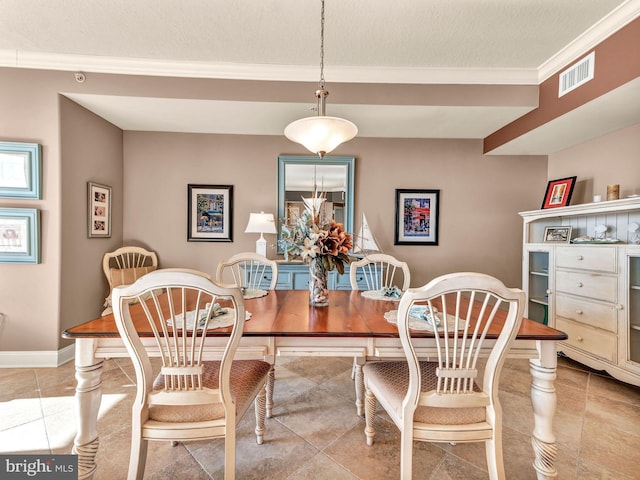 tiled dining space with ornamental molding and a textured ceiling