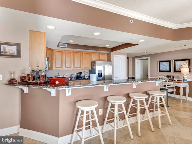 kitchen with a kitchen breakfast bar, stainless steel appliances, kitchen peninsula, and dark stone counters