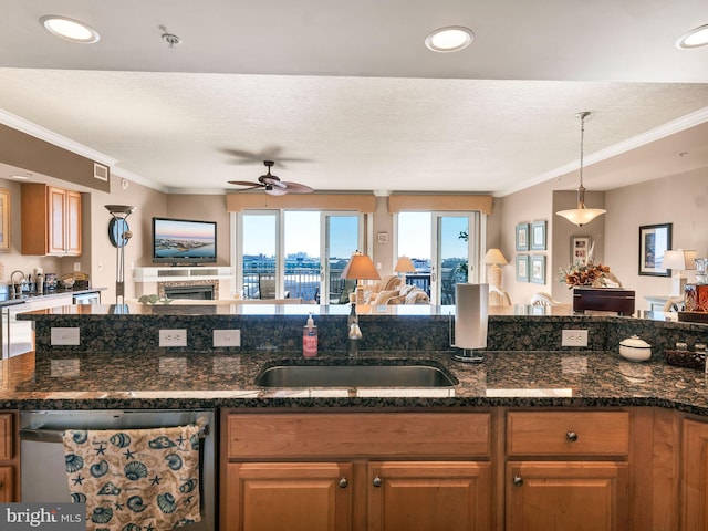 kitchen featuring ceiling fan, dark stone counters, a textured ceiling, stainless steel dishwasher, and sink