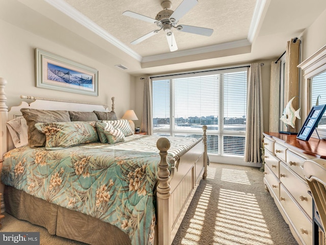 bedroom featuring ceiling fan, a textured ceiling, a tray ceiling, and carpet flooring