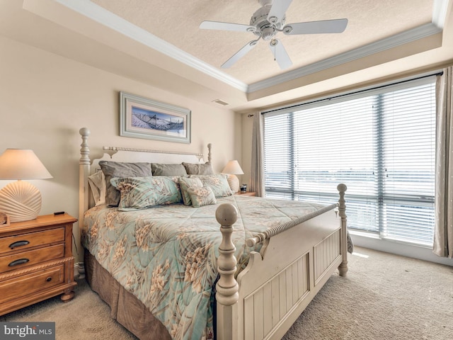 bedroom featuring a raised ceiling, ceiling fan, light carpet, and a textured ceiling