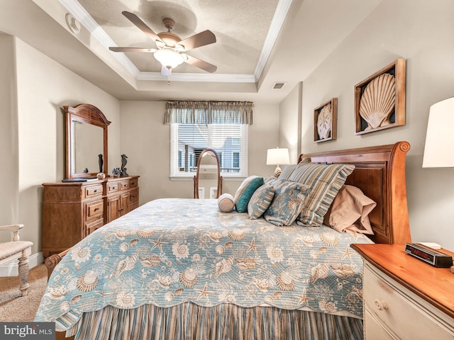 carpeted bedroom featuring ceiling fan, crown molding, and a tray ceiling