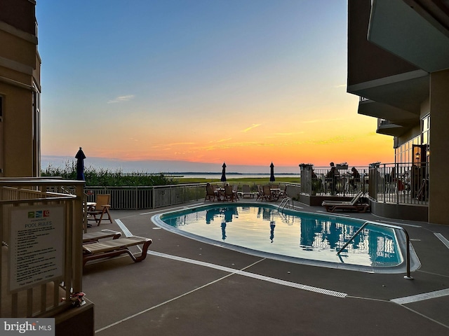 pool at dusk with a patio area