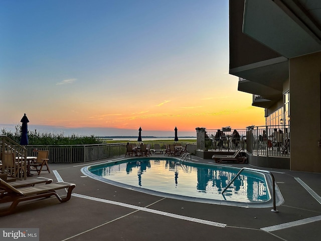 pool at dusk featuring a patio