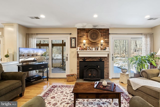 living room featuring a brick fireplace, light hardwood / wood-style flooring, and a healthy amount of sunlight