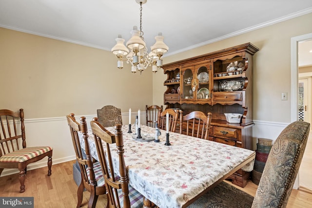 dining space featuring an inviting chandelier, light hardwood / wood-style flooring, and ornamental molding