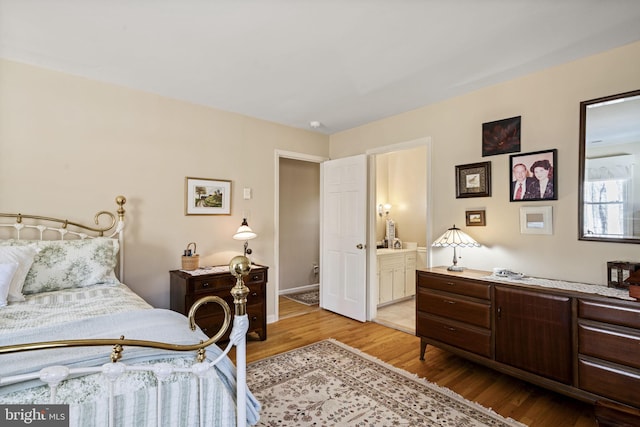 bedroom featuring connected bathroom and light hardwood / wood-style flooring