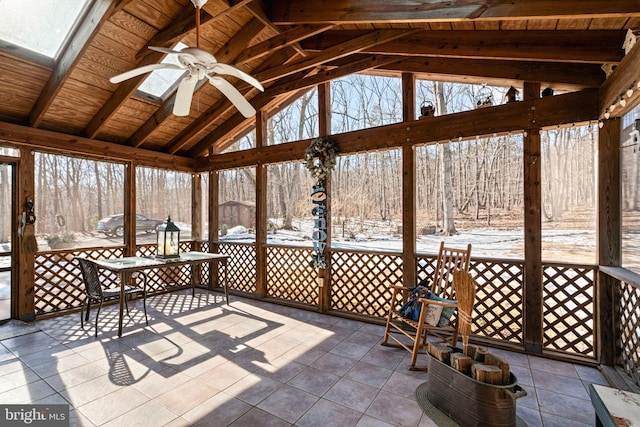 unfurnished sunroom with ceiling fan, a healthy amount of sunlight, vaulted ceiling with skylight, and wooden ceiling