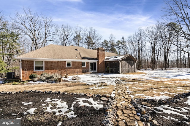 snow covered house featuring a sunroom and central air condition unit