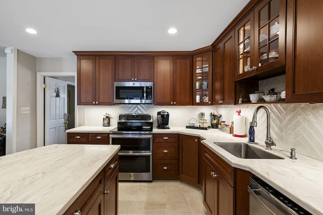 kitchen featuring tasteful backsplash, appliances with stainless steel finishes, sink, and light stone counters