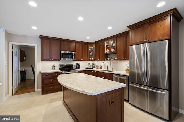 kitchen featuring a kitchen island, sink, decorative backsplash, stainless steel appliances, and dark brown cabinets