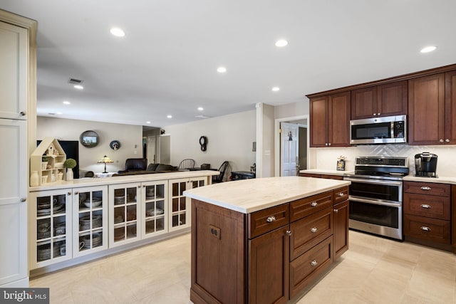 kitchen featuring stainless steel appliances, a kitchen island, dark brown cabinets, and decorative backsplash