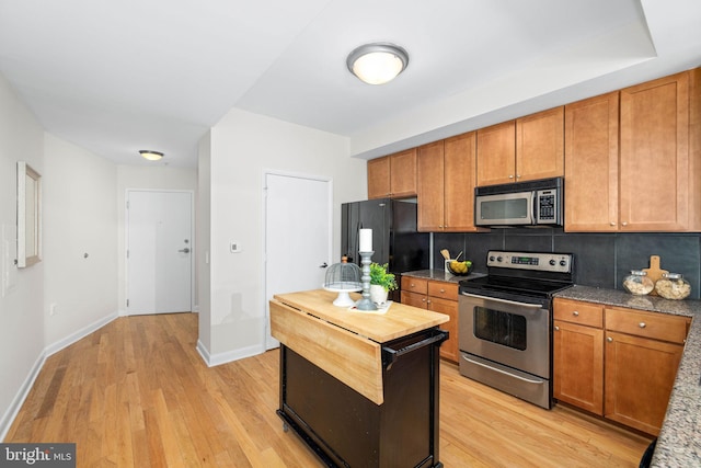 kitchen featuring appliances with stainless steel finishes, light hardwood / wood-style flooring, and backsplash