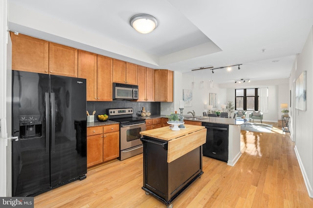 kitchen featuring light hardwood / wood-style floors, kitchen peninsula, decorative backsplash, black appliances, and sink