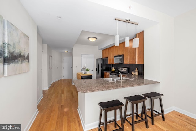 kitchen featuring a kitchen bar, backsplash, black fridge, kitchen peninsula, and electric range