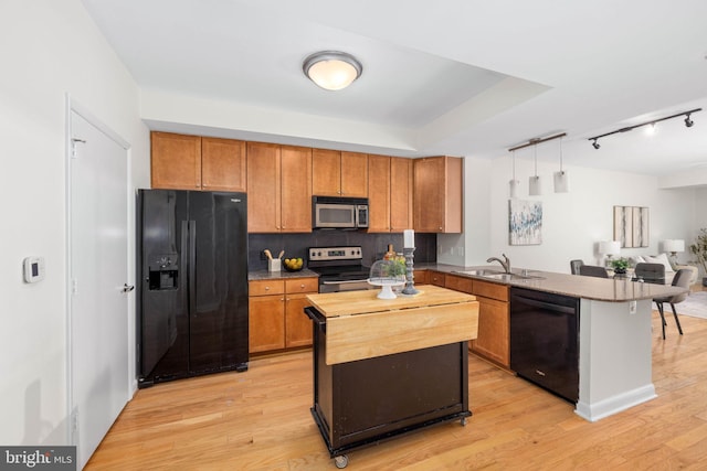 kitchen with black appliances, sink, light hardwood / wood-style floors, and pendant lighting