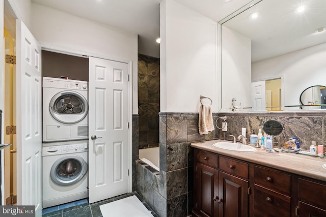 interior space with stacked washer and dryer, sink, and tile walls